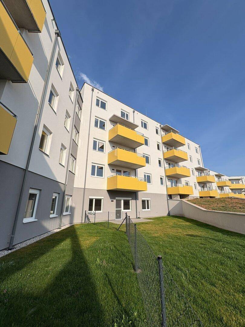 Moderne Wohnanlage mit markanten gelben Balkonen und gepflegten Grünflächen.