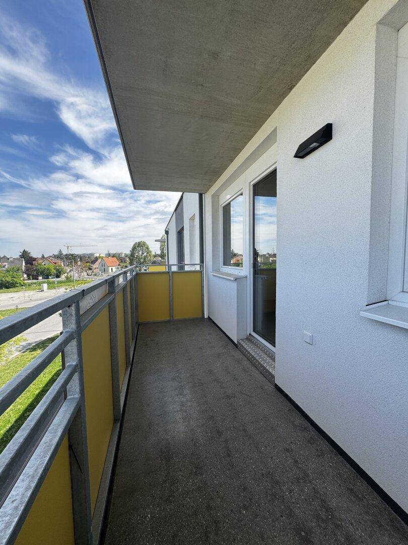 Geräumiger Balkon mit gelben Paneelen und weitem Blick auf die Stadt.