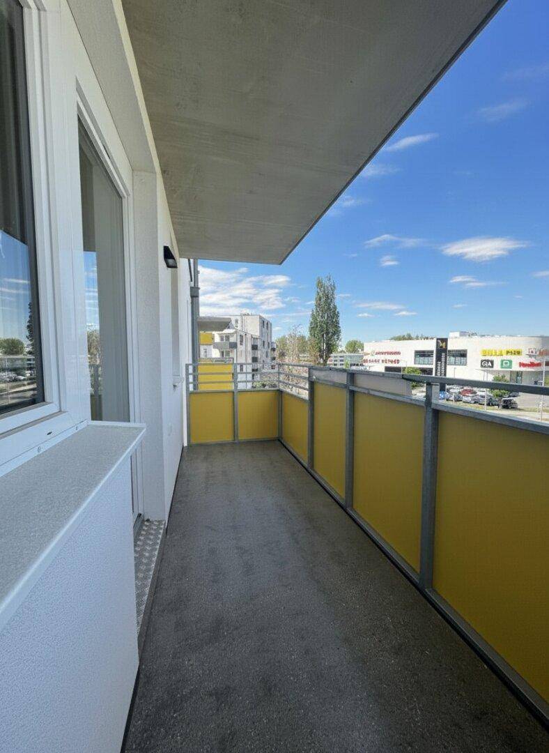 Langer Balkon mit gelben Sichtschutzelementen und Blick auf die Umgebung.