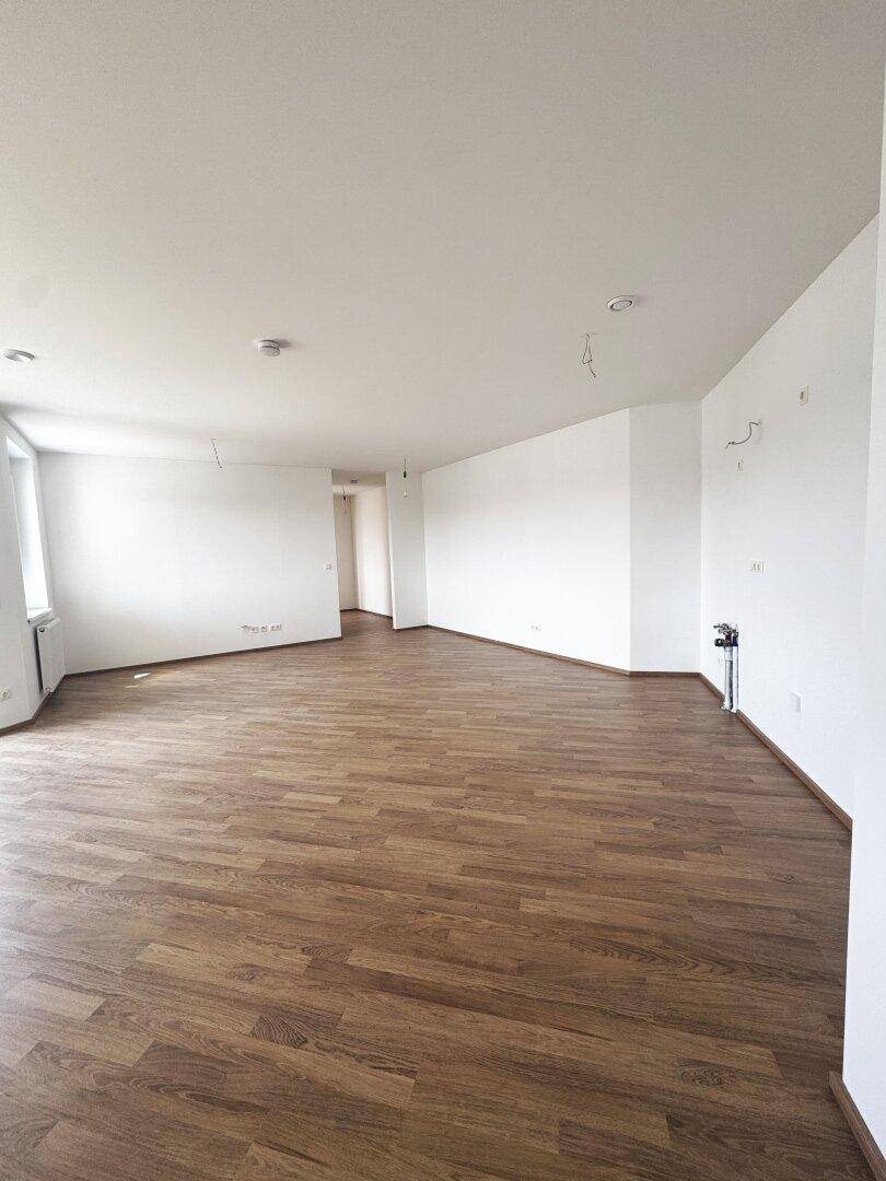 Großer, heller Raum mit Laminatboden und weißen Wänden, vorbereitet für individuelle Gestaltung.