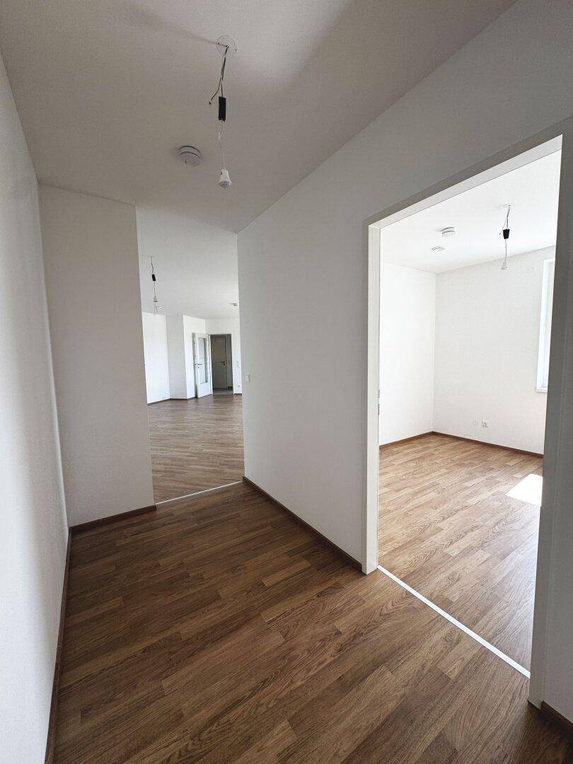 Heller Flur mit Laminatboden, der zu verschiedenen Zimmern der Wohnung führt.
