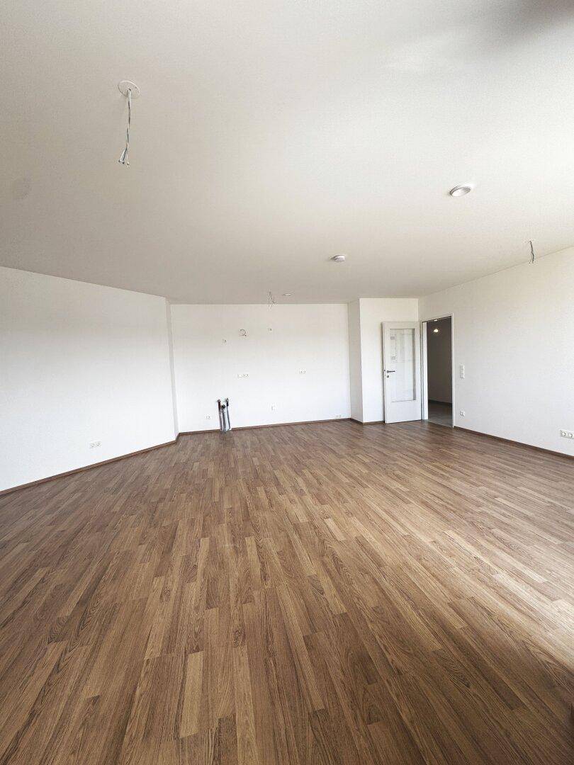 Heller Wohnraum mit Laminatboden und weißen Wänden, bereit für die Einrichtung.