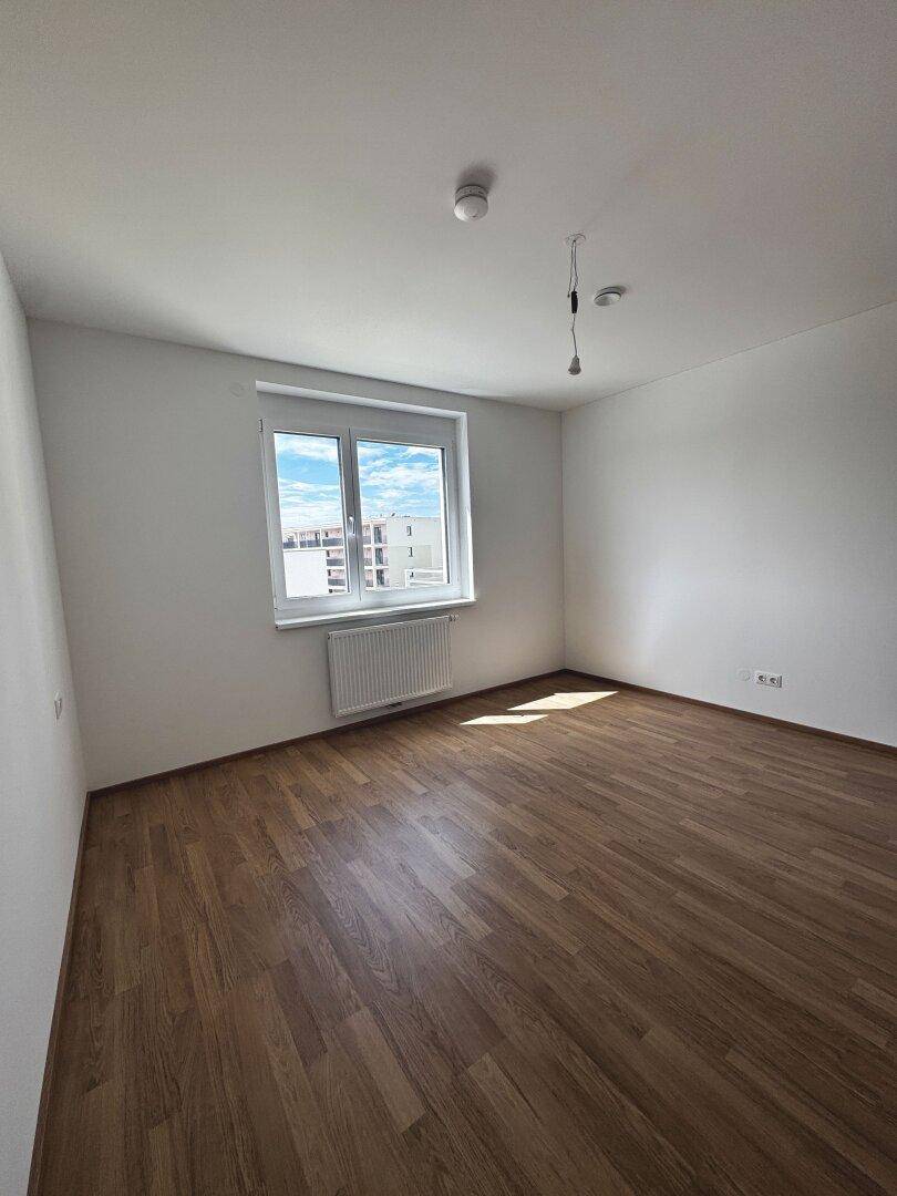 Geräumiges Schlafzimmer mit Laminatboden und weiß gestrichenen Wänden, bereit zur Einrichtung.