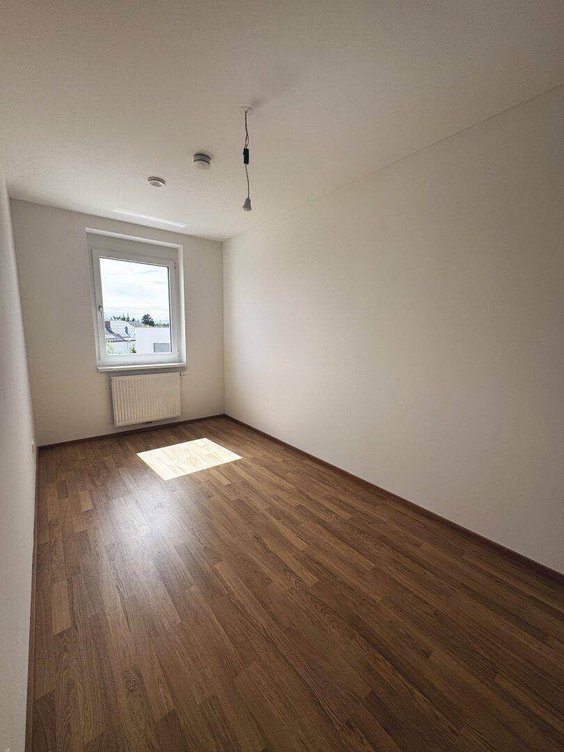 Ruhiges Schlafzimmer mit Laminatboden und weißer Wandgestaltung, ideal für Erholung.