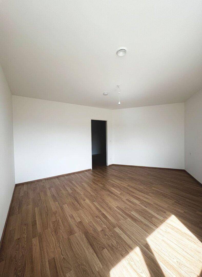 Geräumiges Zimmer mit Laminatboden und weiß gestrichenen Wänden, bereit zum Einzug.
