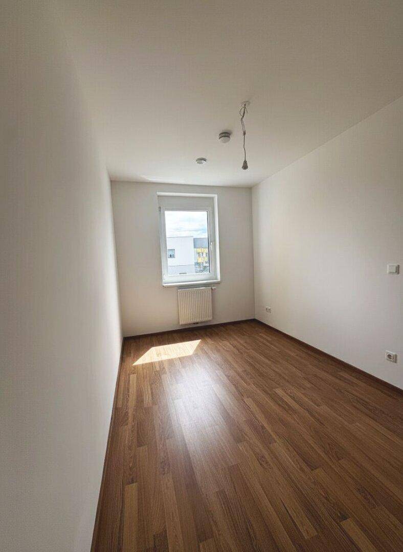 Kleineres Zimmer mit Laminatboden und Fenster, ideal als Kinderzimmer oder Arbeitszimmer.