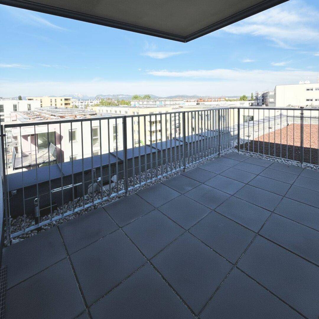 Weitläufige Terrasse mit dunklen Bodenfliesen und Panoramablick über die Stadt und die umliegende Landschaft.
