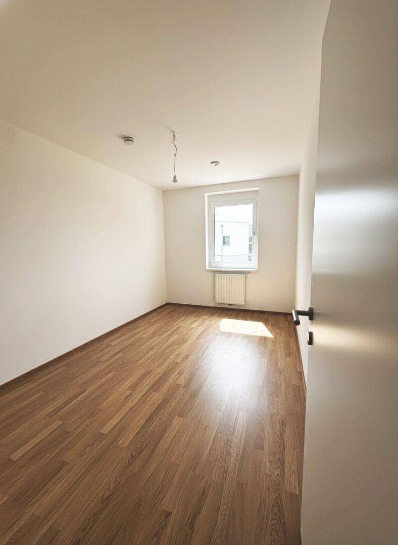 Schlafzimmer mit Laminatboden, Fenster und Heizkörper, ideal für individuelle Gestaltung.