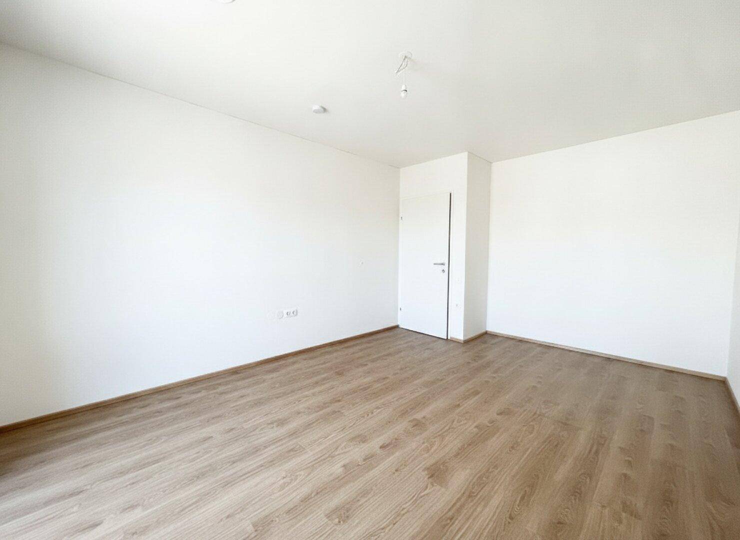 Leeres Zimmer mit Laminatboden und weißen Wänden, bietet flexible Nutzungsmöglichkeiten als Schlaf- oder Arbeitszimmer.