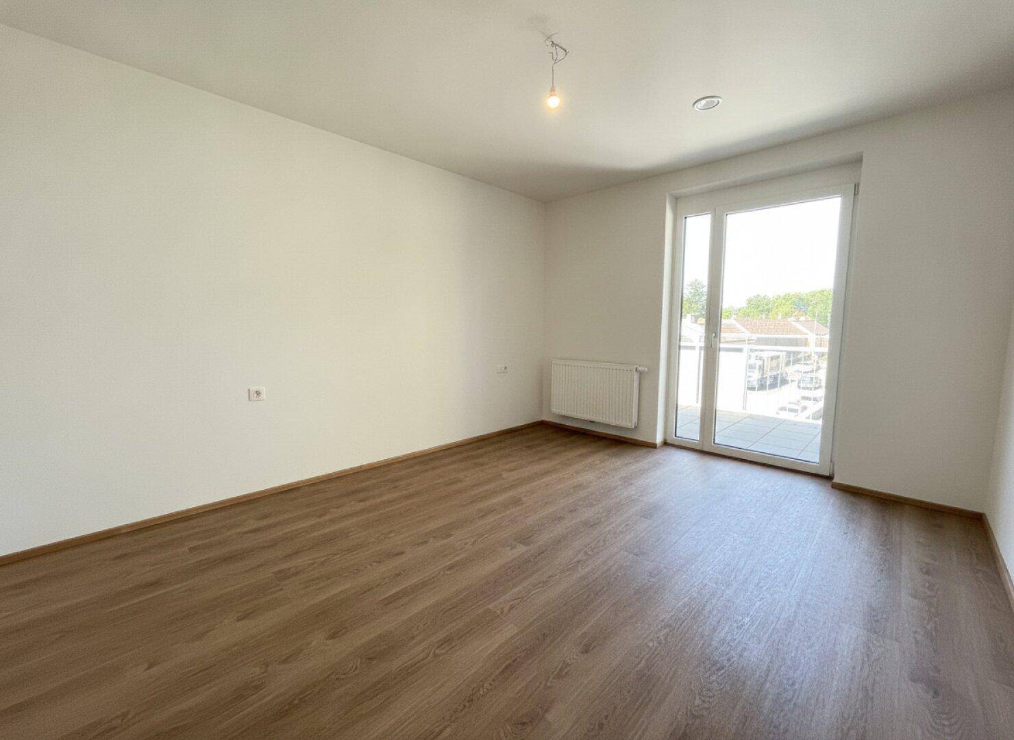Helles Schlafzimmer mit Laminatboden und direktem Zugang zu einem Außenbereich, ideal für frische Luft.