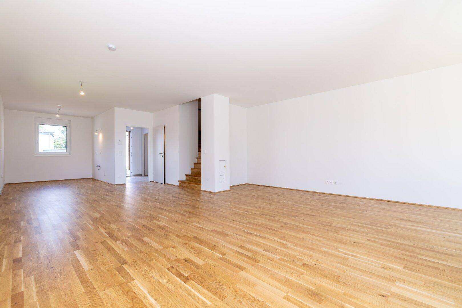 Geräumiger offener Wohnbereich mit Eichenparkettboden und Treppe zum Obergeschoss.