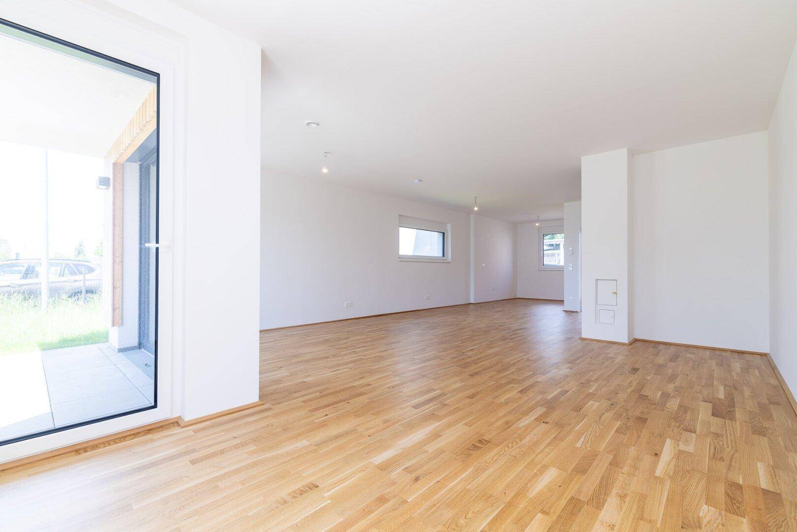 Helles, offenes Wohnzimmer mit Eichenparkettboden und direktem Zugang zur Terrasse.