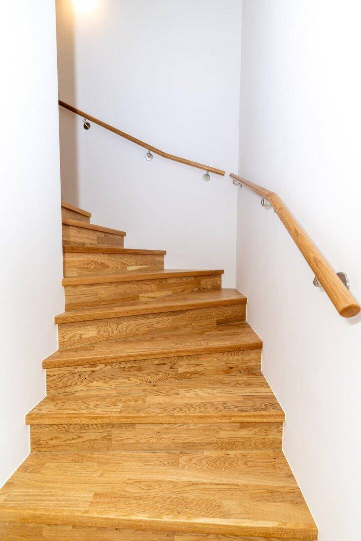 Holztreppe mit modernem Geländer, die die verschiedenen Etagen des Hauses verbindet.