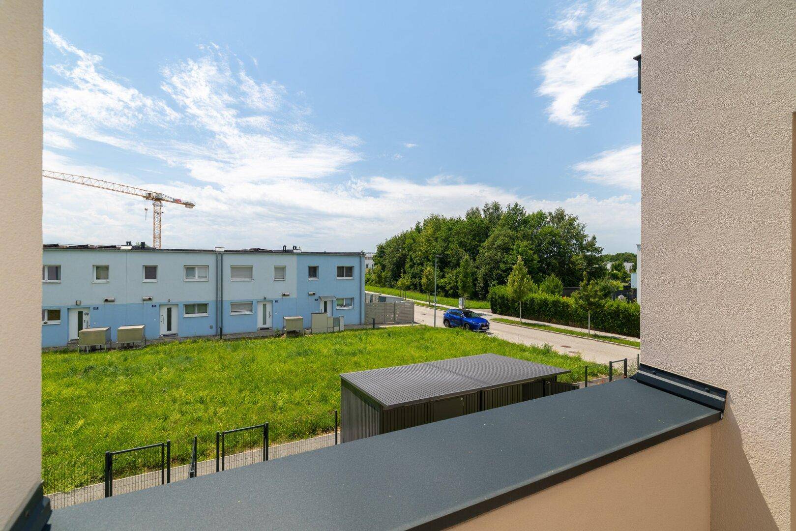 Balkon mit weitem Blick über die grüne Landschaft und die umliegende Wohnsiedlung.