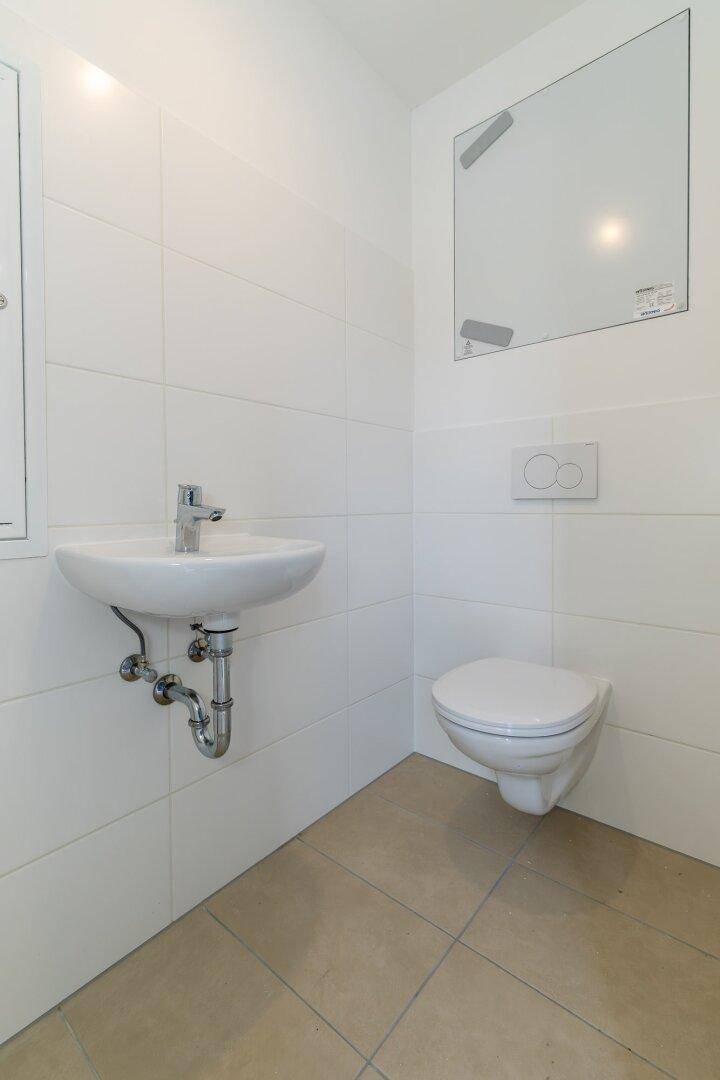 Kleines Gäste-WC mit wandhängendem WC und modernem Waschbecken, in schlichtem Design.