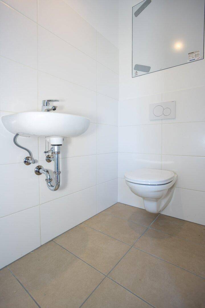 Kleines Gäste-WC mit Waschbecken und wandhängendem WC, modern gefliest.