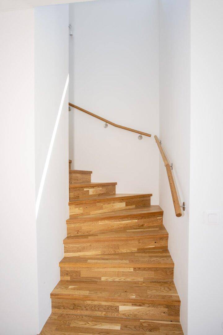 Moderne Holztreppe mit schlichtem Handlauf, die die verschiedenen Etagen des Hauses verbindet.