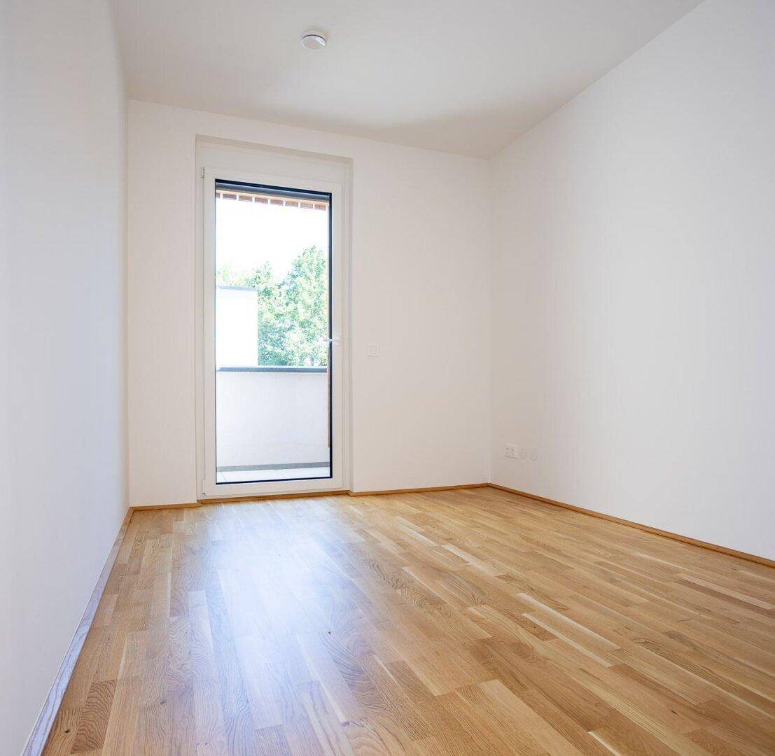 Helles Schlafzimmer mit Eichenparkett und Zugang zu einem französischen Balkon, bietet viel Tageslicht.