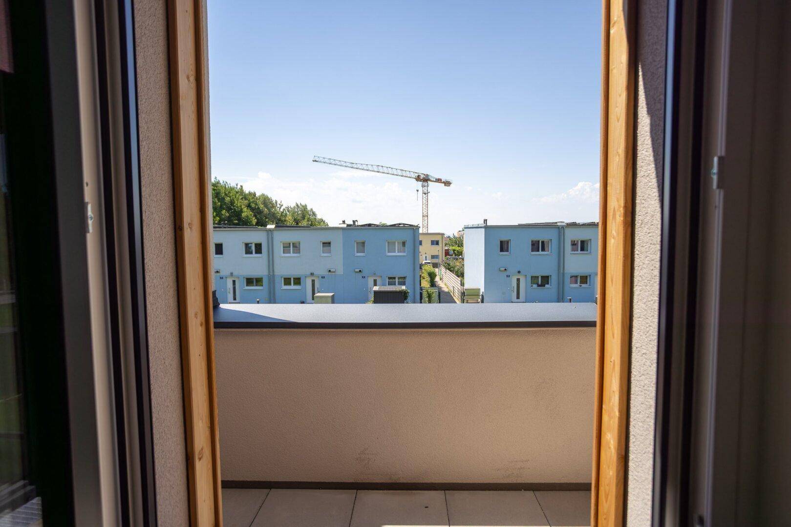 Blick vom Balkon auf die umliegenden Gebäude und eine Baustelle mit Kran unter klarem Himmel.