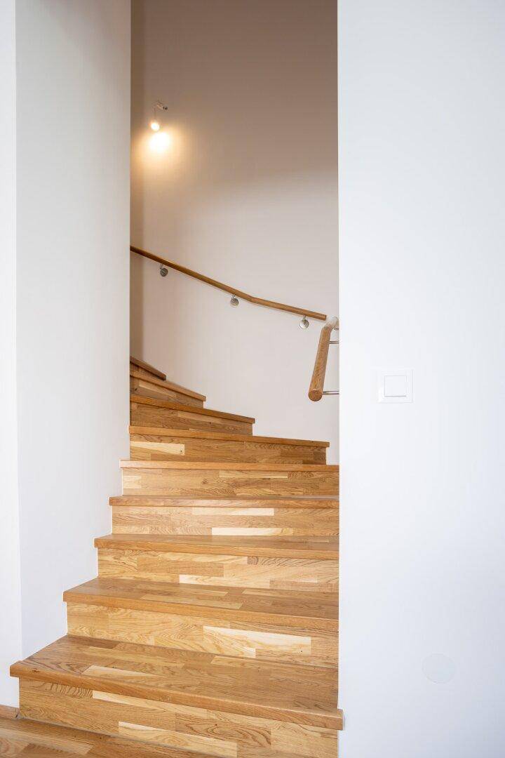 Elegante Holztreppe mit modernem Geländer, die die verschiedenen Etagen des Hauses verbindet.