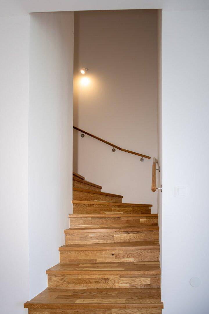 Moderne Holztreppe mit Handlauf, die die verschiedenen Etagen verbindet.