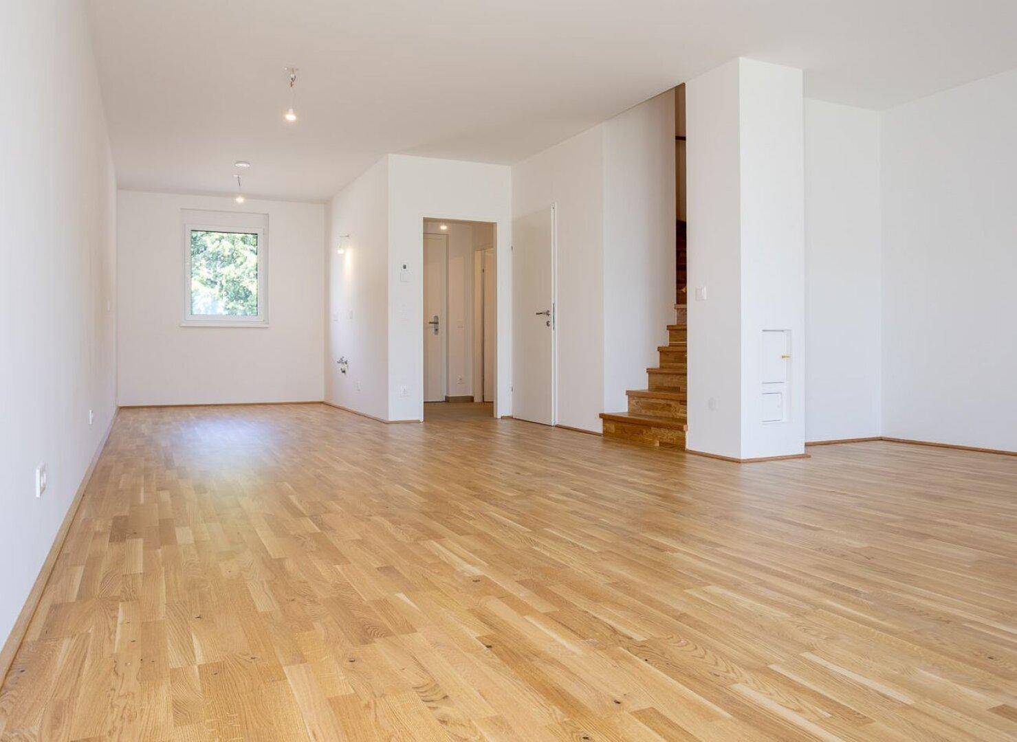 Offener Wohnbereich mit Eichenparkettboden und Holztreppe zum Obergeschoss.
