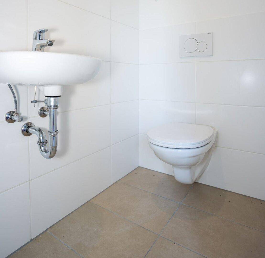Modernes Badezimmer mit wandhängendem WC und stilvollem Waschbecken.
