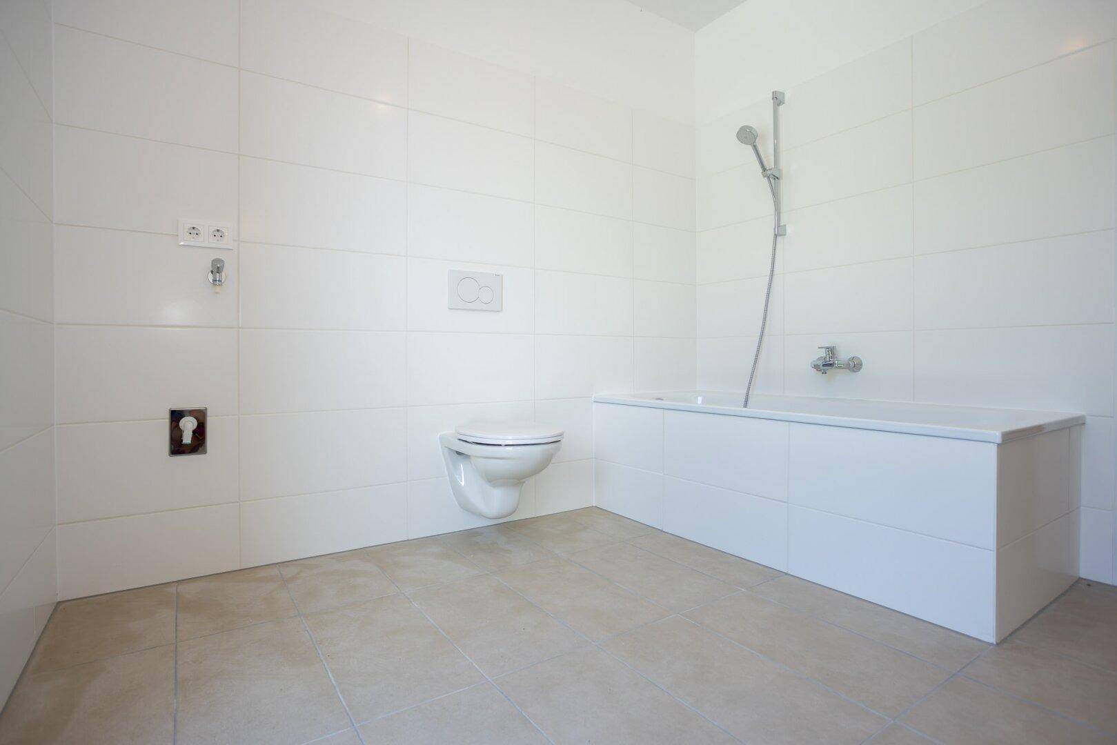 Helles Badezimmer mit Badewanne und wandhängendem WC.