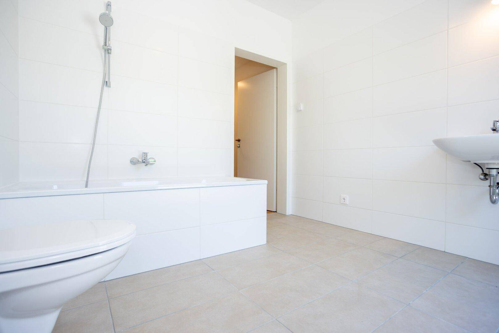 Modernes Badezimmer mit Badewanne, WC und Waschbecken.