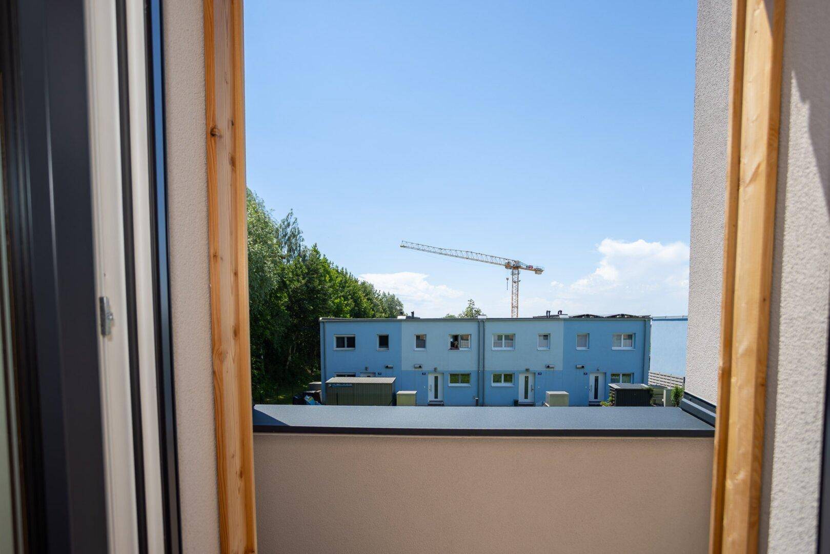 Blick aus dem Fenster auf benachbarte Gebäude und einen Baukran.