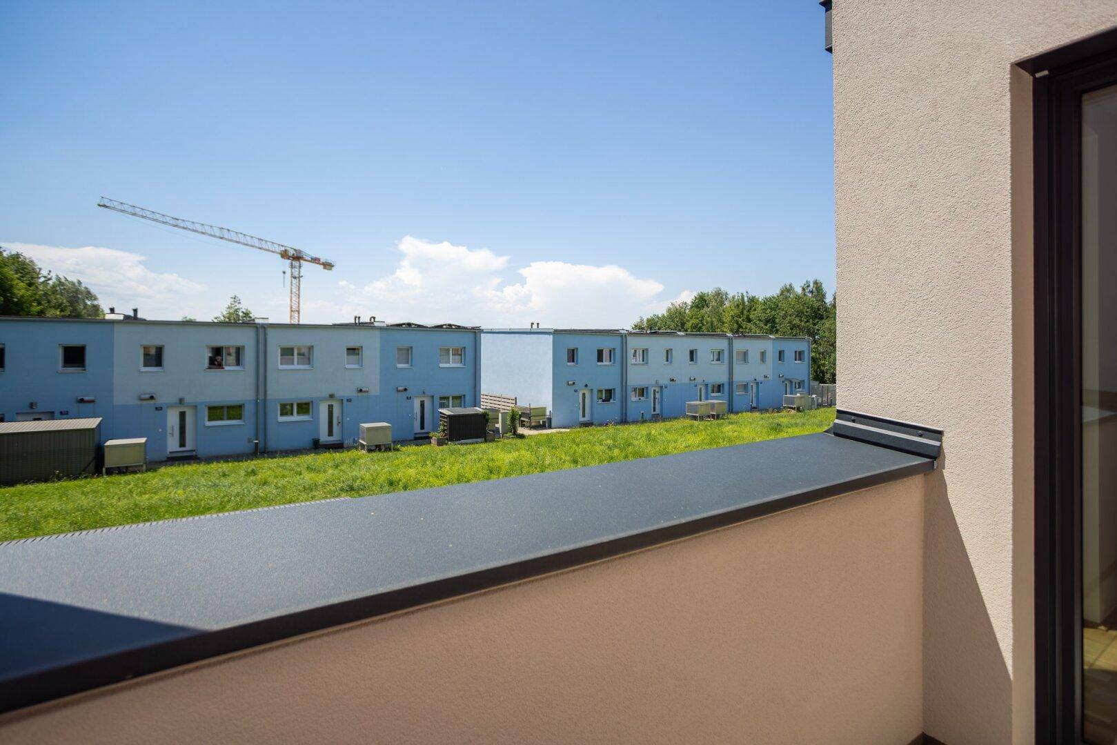 Weitblick über die Nachbarschaft mit blauen Häusern und einem Baukran.