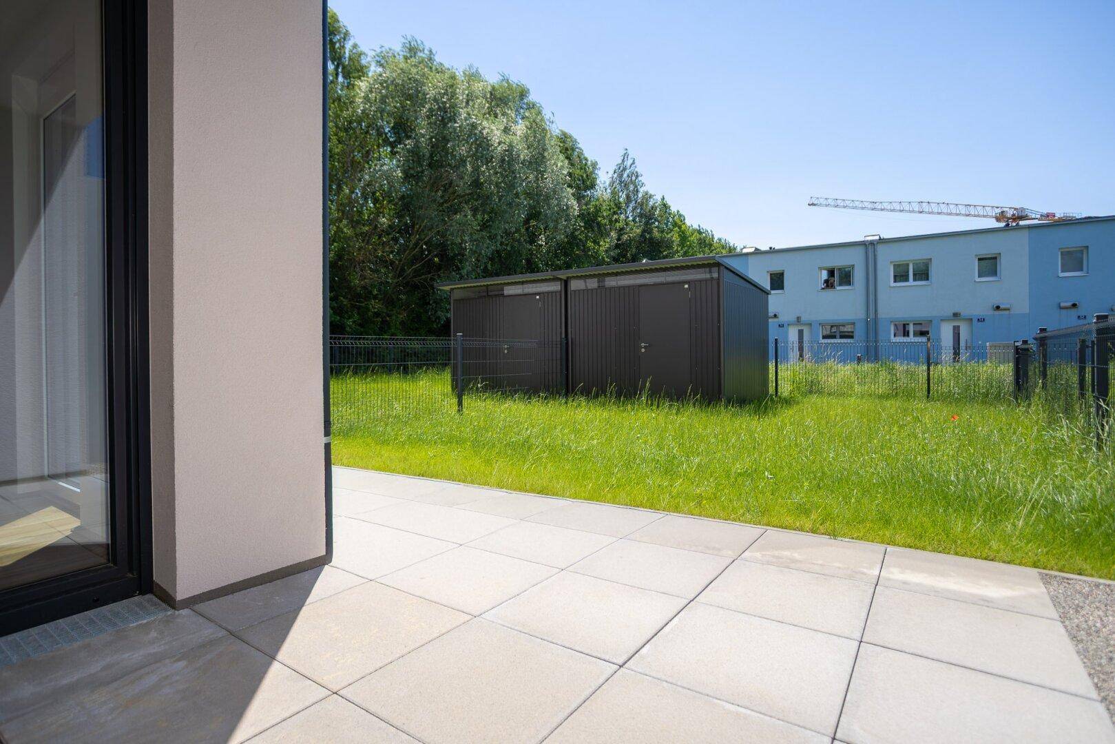 Geräumige Terrasse mit hellen Fliesen und Blick auf den Gartenbereich.