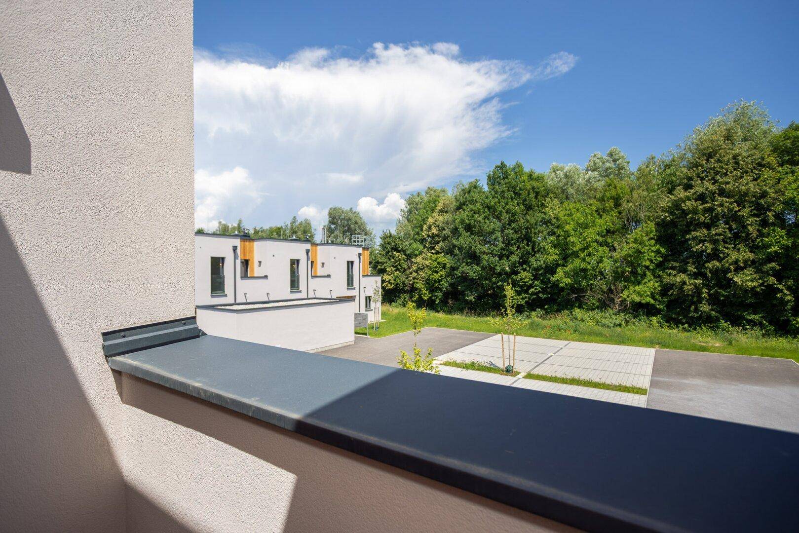Ausblick auf moderne Reihenhäuser und einen Parkplatz unter blauem Himmel.
