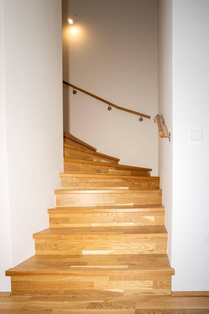 Moderne Holztreppe mit schlichtem Geländer führt in die obere Etage des Hauses.
