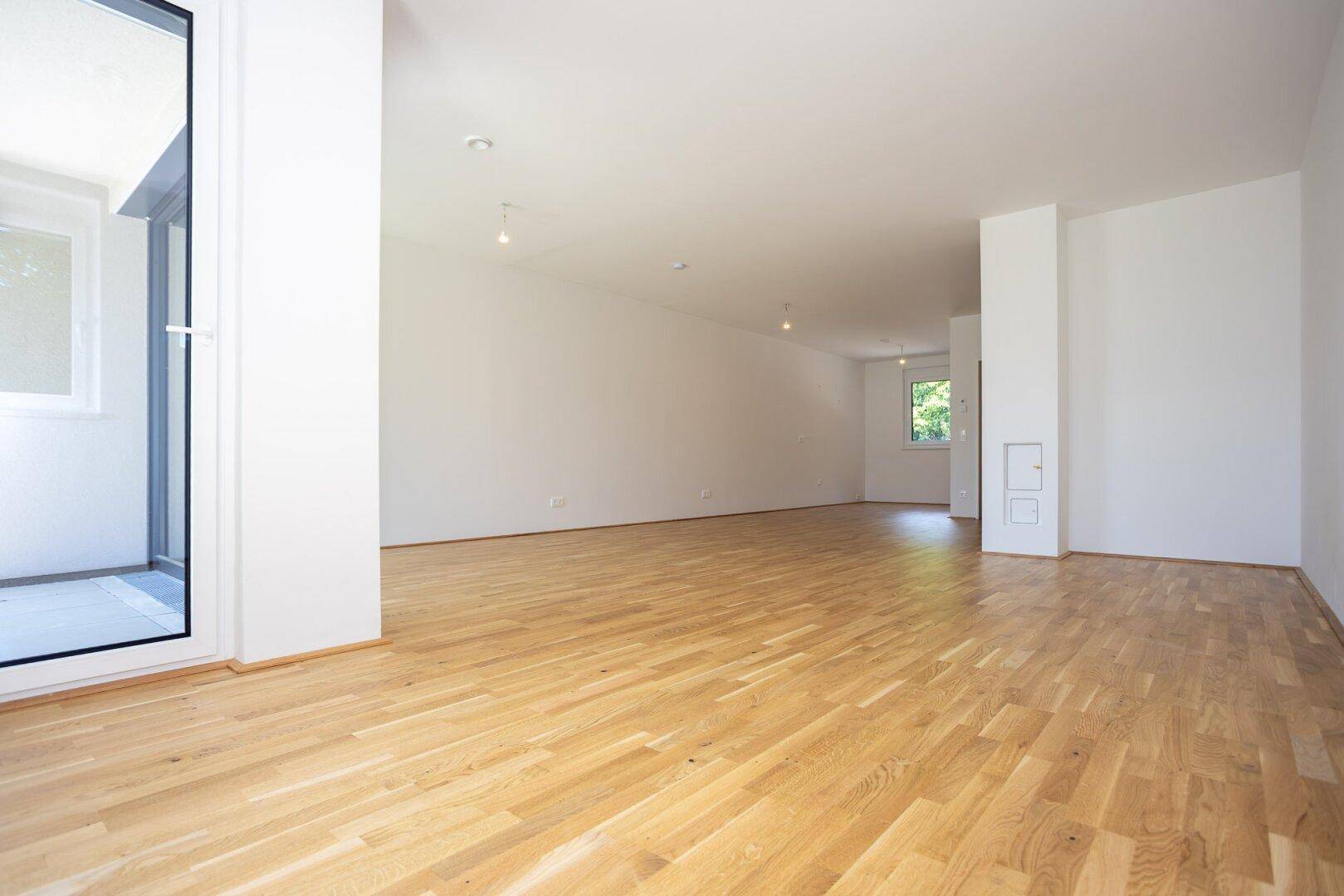 Geräumiger, heller Raum mit Eichenparkett und Zugang zu einem kleinen Balkon.