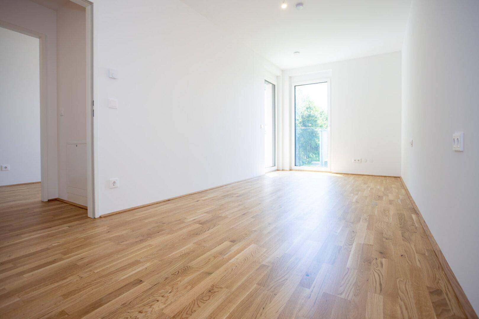 Geräumiger, heller Raum mit Eichenparkett und zwei großen Fenstertüren zum Balkon.
