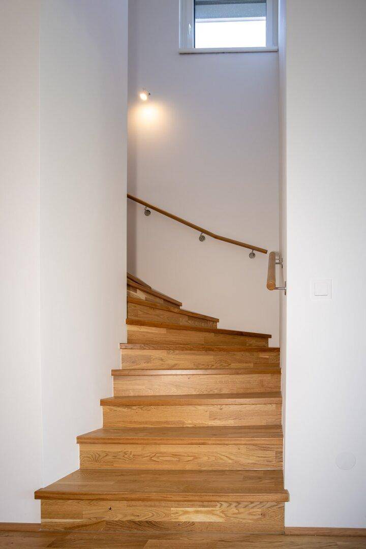 Moderne Holztreppe mit schlichtem Geländer, die in das obere Stockwerk führt.