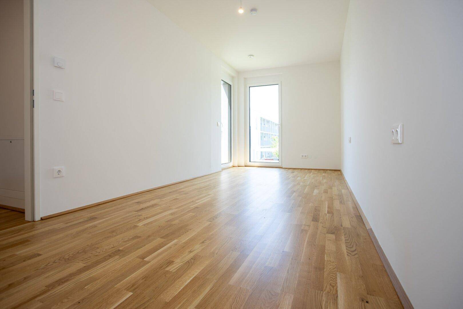 Geräumiges Schlafzimmer mit Parkettboden und großen Fenstern, die viel Licht spenden.