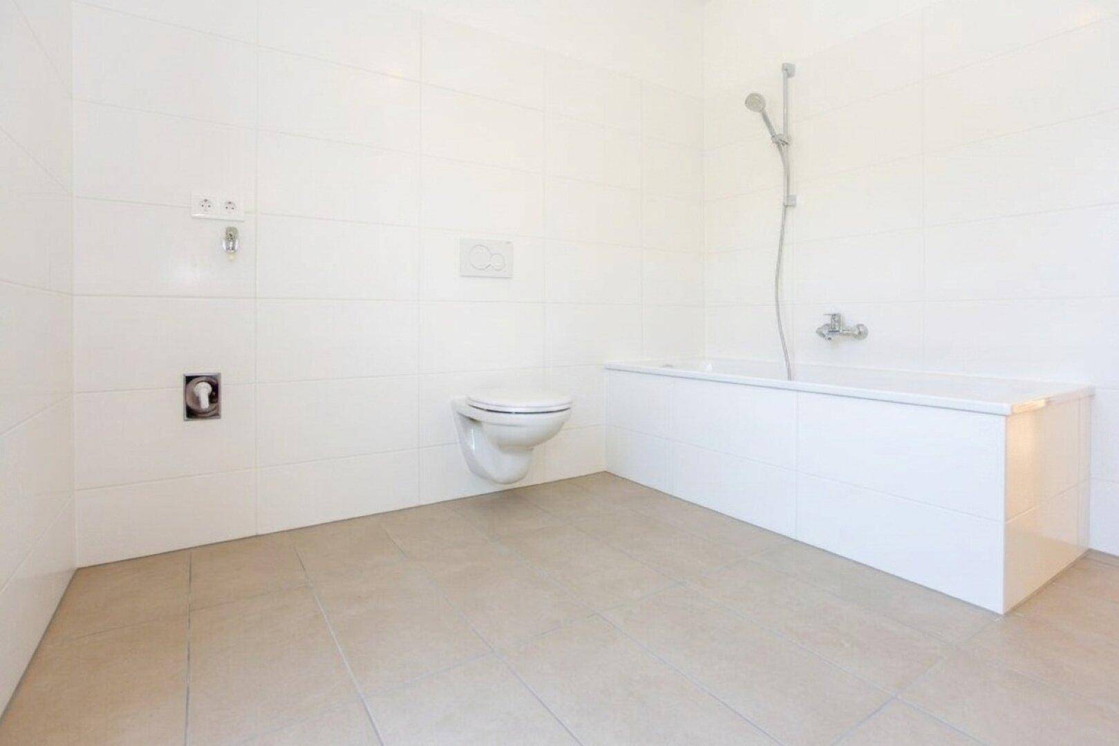 Helles Badezimmer mit Badewanne, wandhängendem WC und modernen Fliesen an Wänden und Boden.