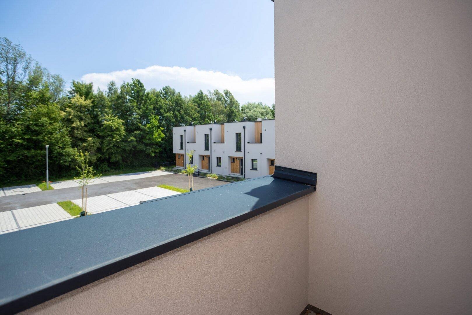 Aussicht vom Balkon auf weitere moderne Reihenhäuser und die umliegende grüne Landschaft.