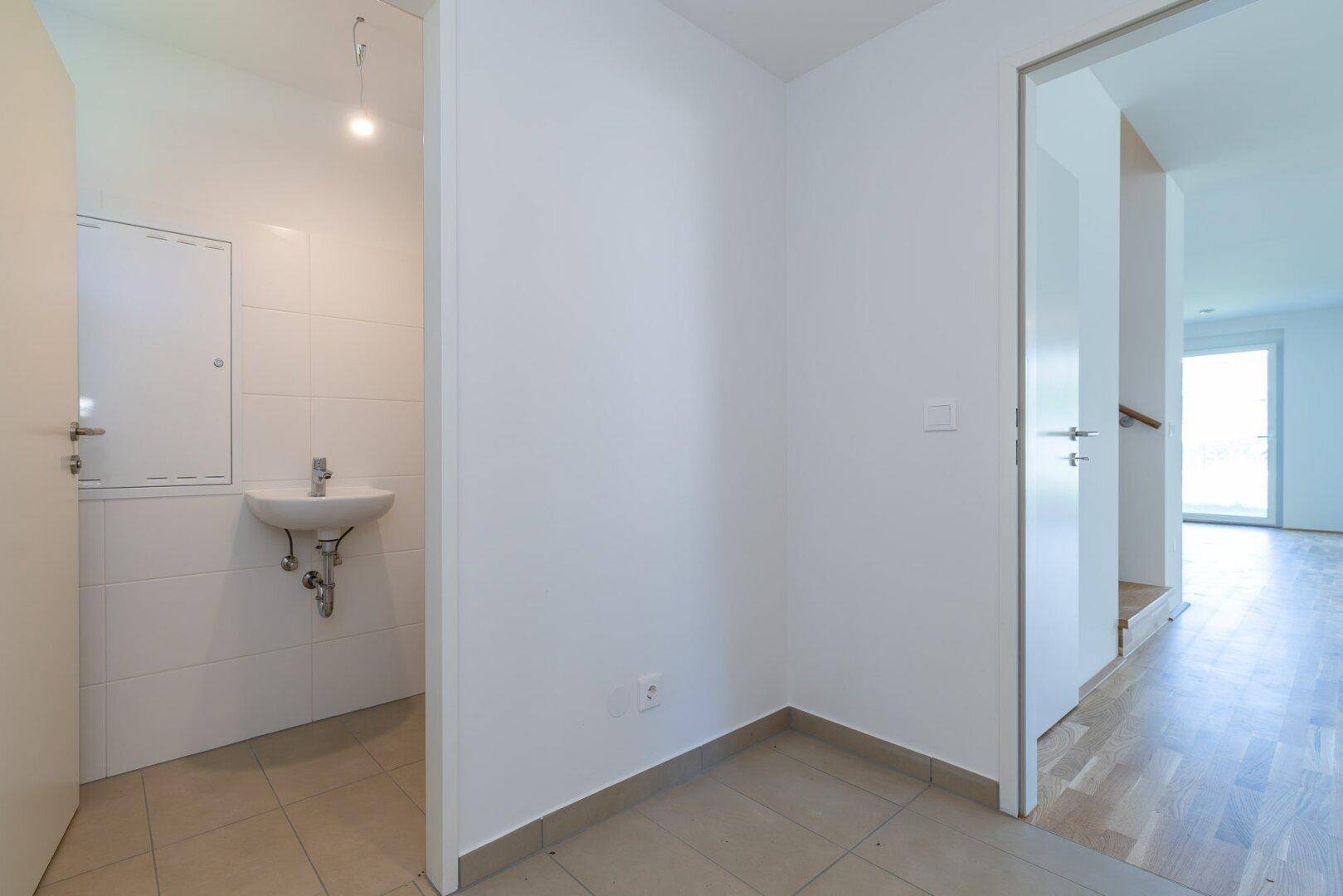 Heller Eingangsbereich mit gefliestem Boden und Zugang zu einem Gäste-WC.