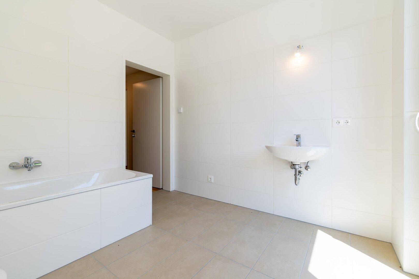 Modernes Badezimmer mit Badewanne und Waschbecken, hell gefliest und funktional.