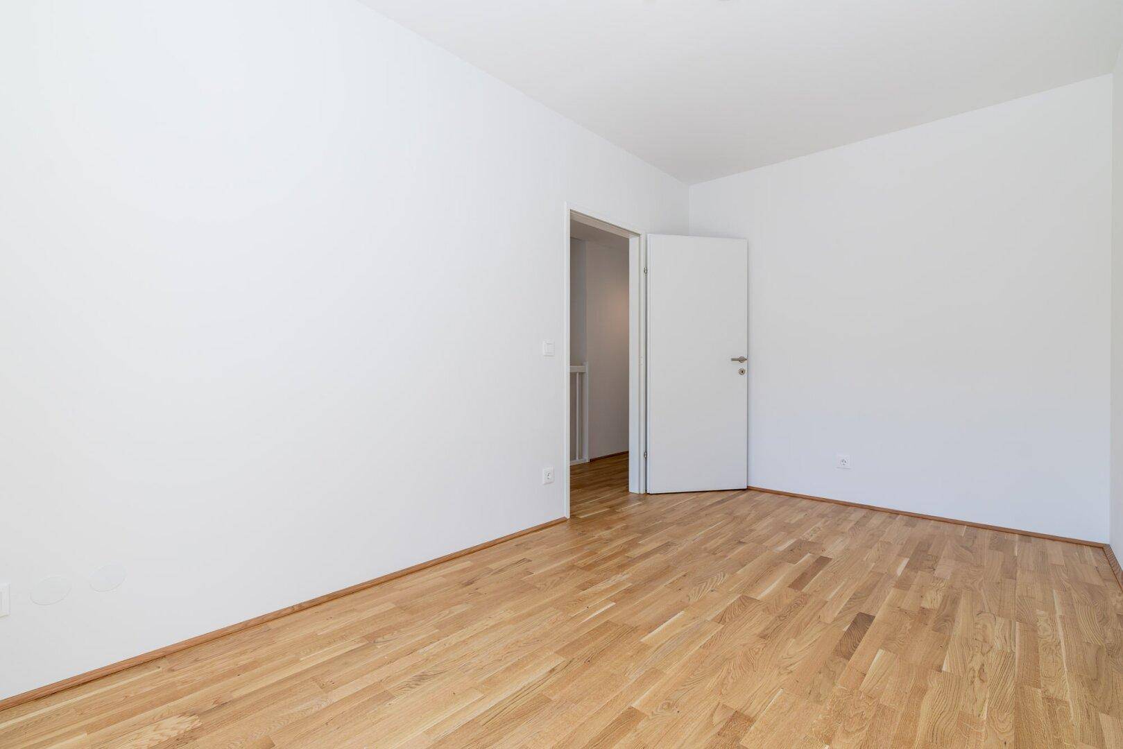Leeres, helles Zimmer mit Parkettboden und weiß gestrichenen Wänden, bereit zur Einrichtung.