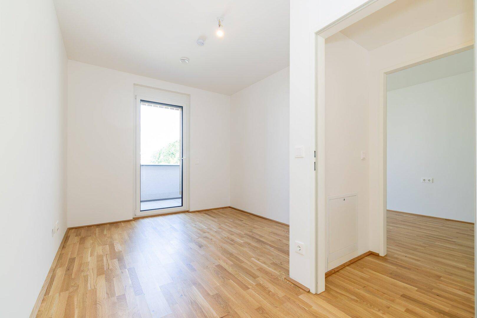 Helles Zimmer mit Parkettboden und Balkonzugang, ideal als Schlaf- oder Arbeitszimmer.