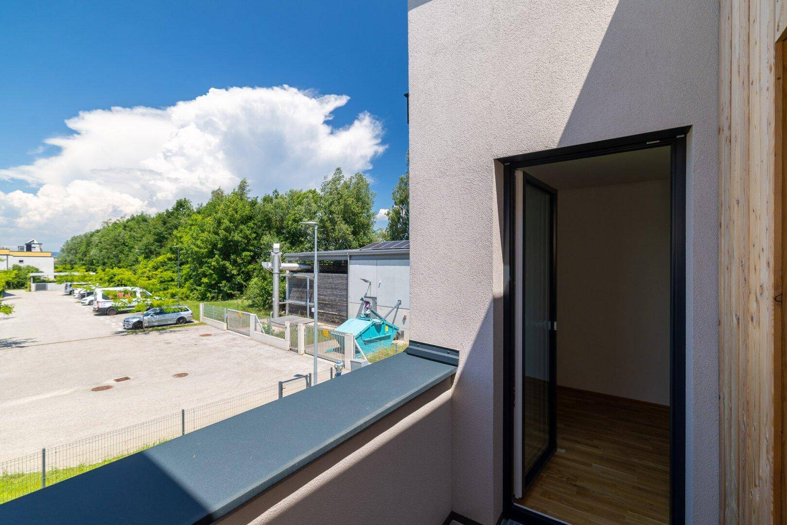 Balkon mit Blick auf den Außenbereich und angrenzende Gebäude, mit offener Tür zum Innenraum.