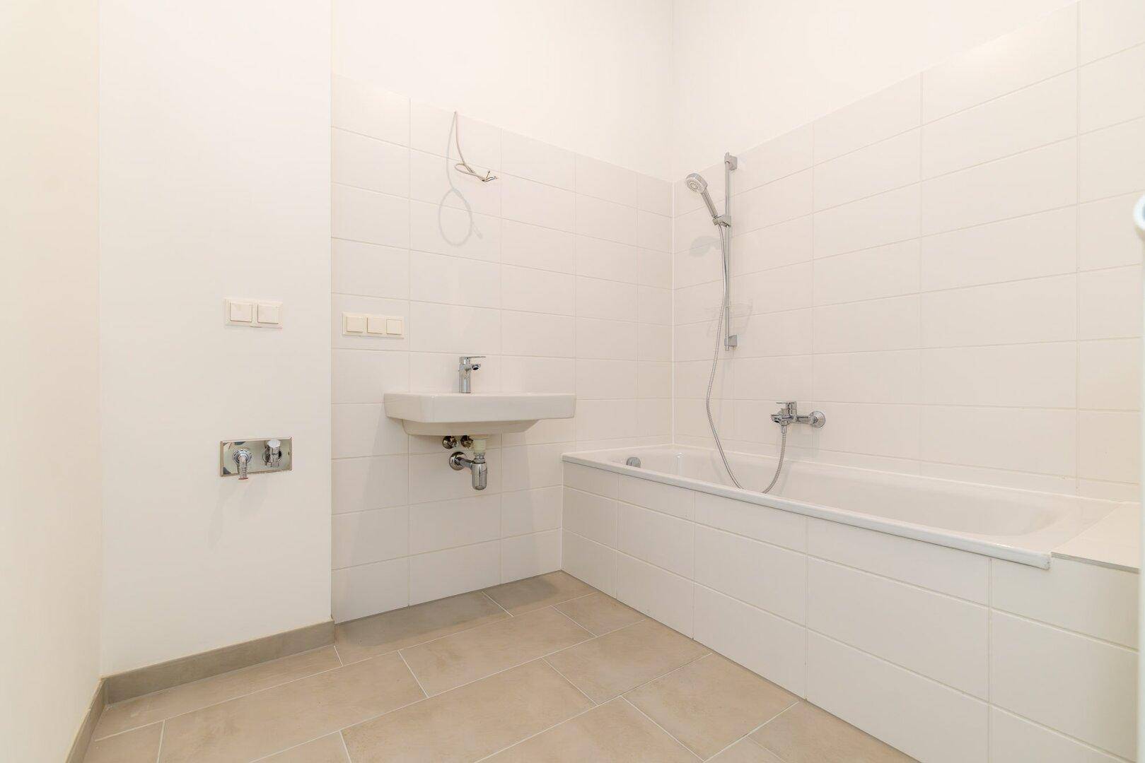 Modernes Badezimmer mit weiß gefliesten Wänden, Badewanne und Waschbecken.