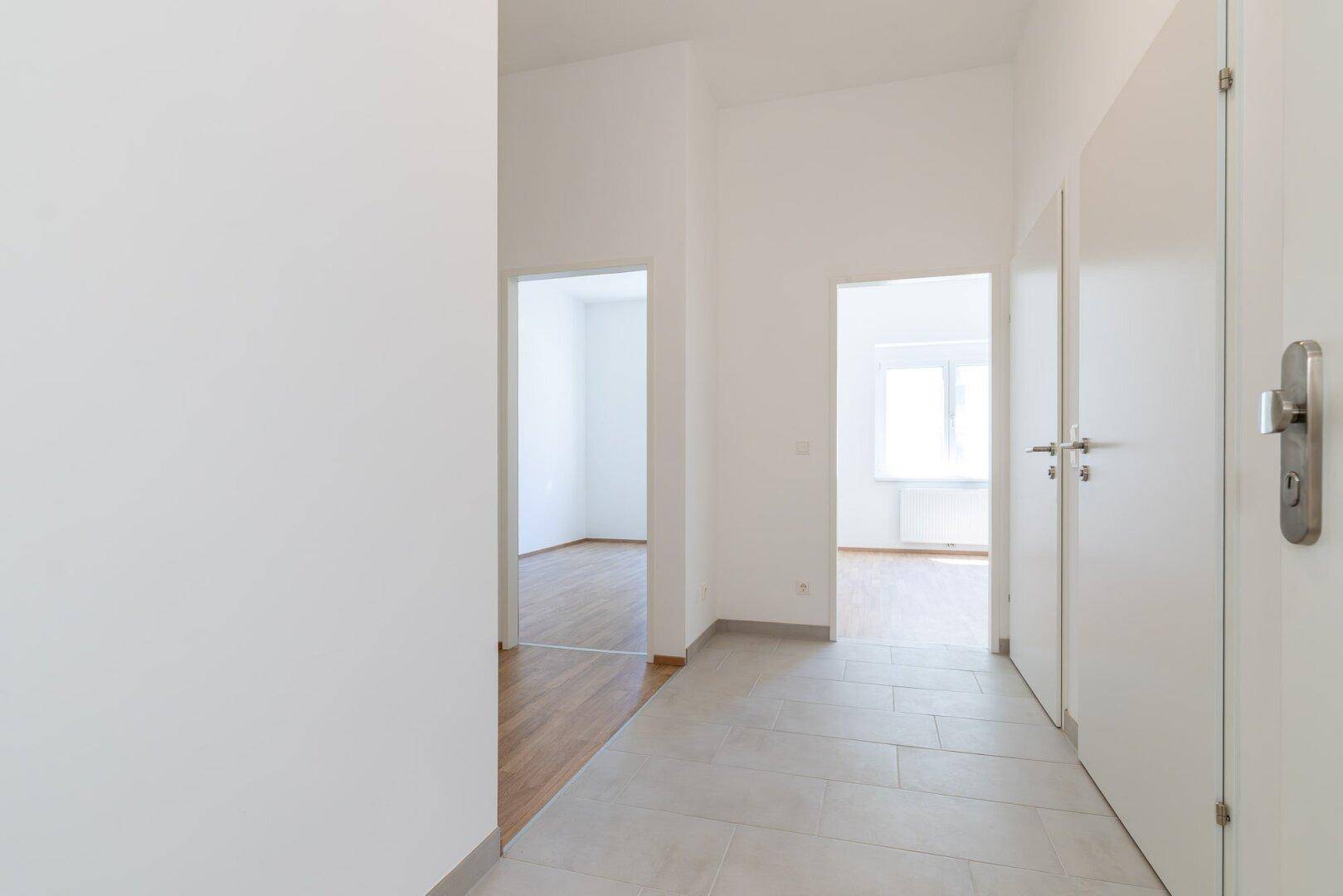 Lichtdurchfluteter Flur mit Laminat- und Fliesenboden sowie mehreren Zimmertüren.