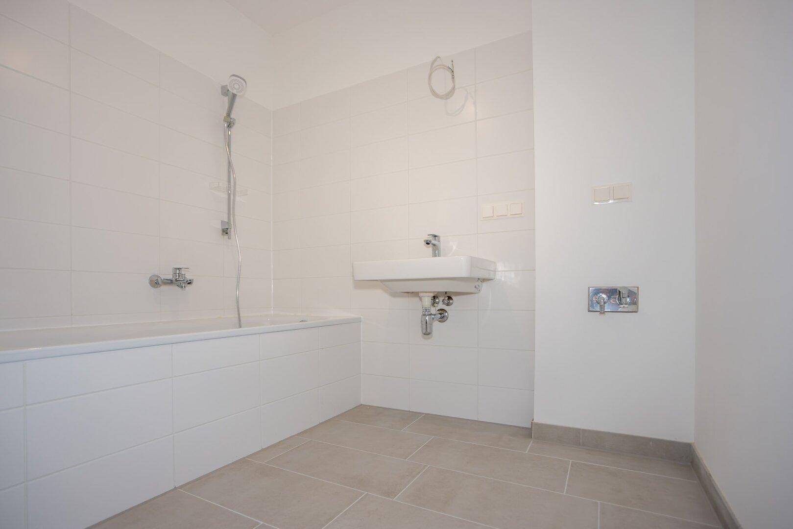 Modernes Badezimmer mit Badewanne, Waschbecken und weißen Fliesen.