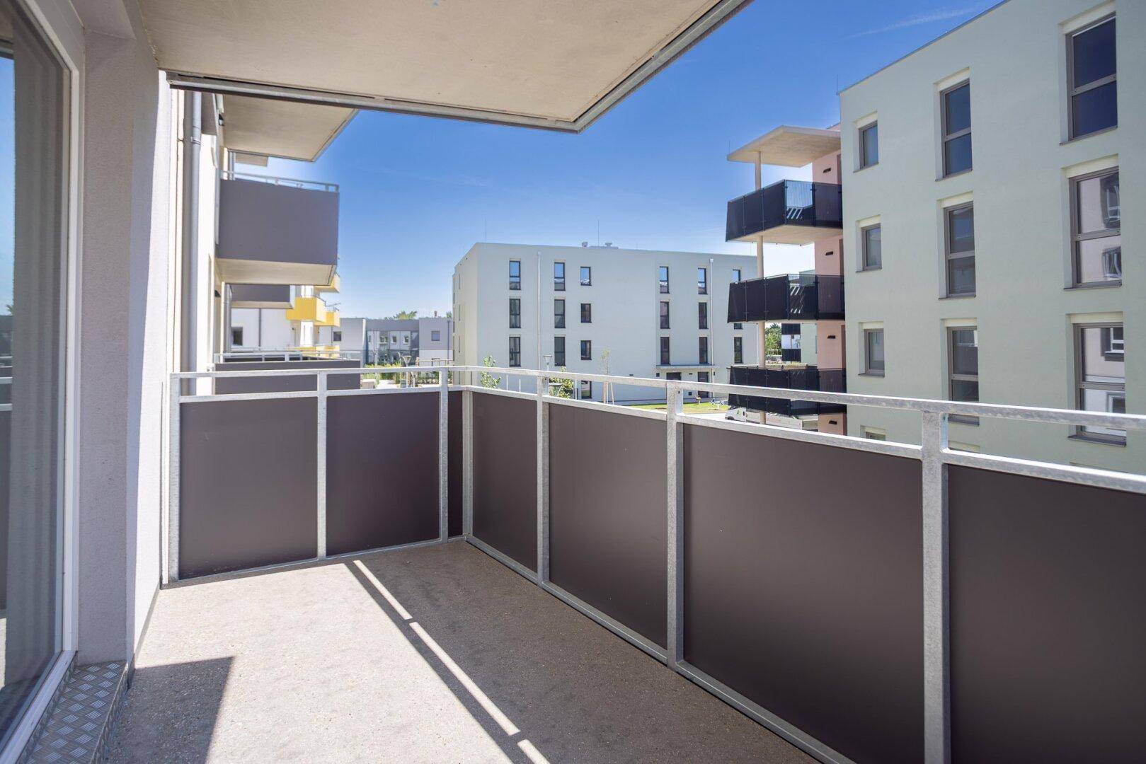 Heller Balkon mit moderner Brüstung und Ausblick auf die benachbarten Wohnkomplexe.