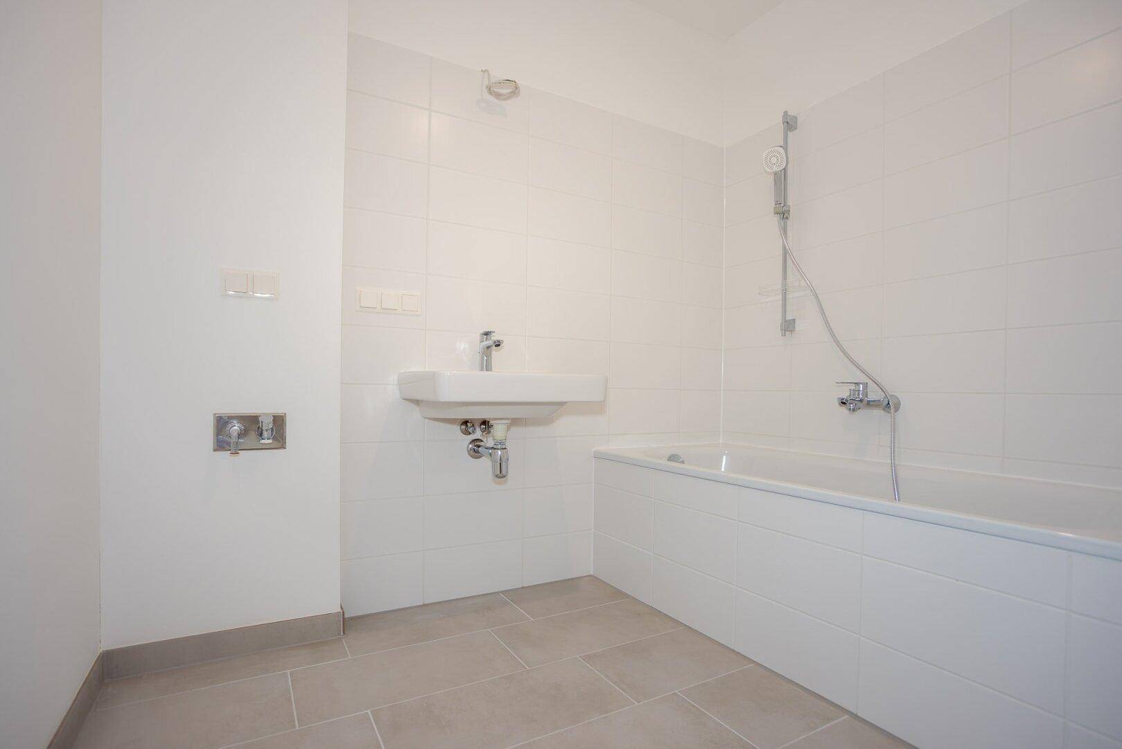 Modernes Badezimmer mit Badewanne, Waschbecken und weißen Fliesen an den Wänden.